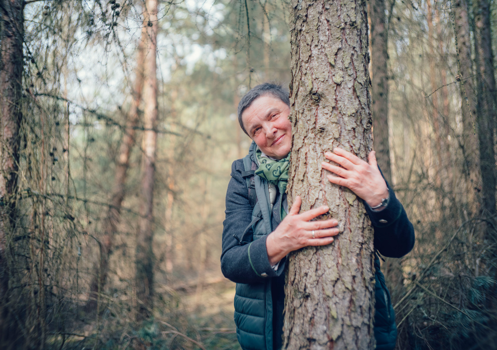 a woman with short hair hugs a tree in the forest - conversation graphic