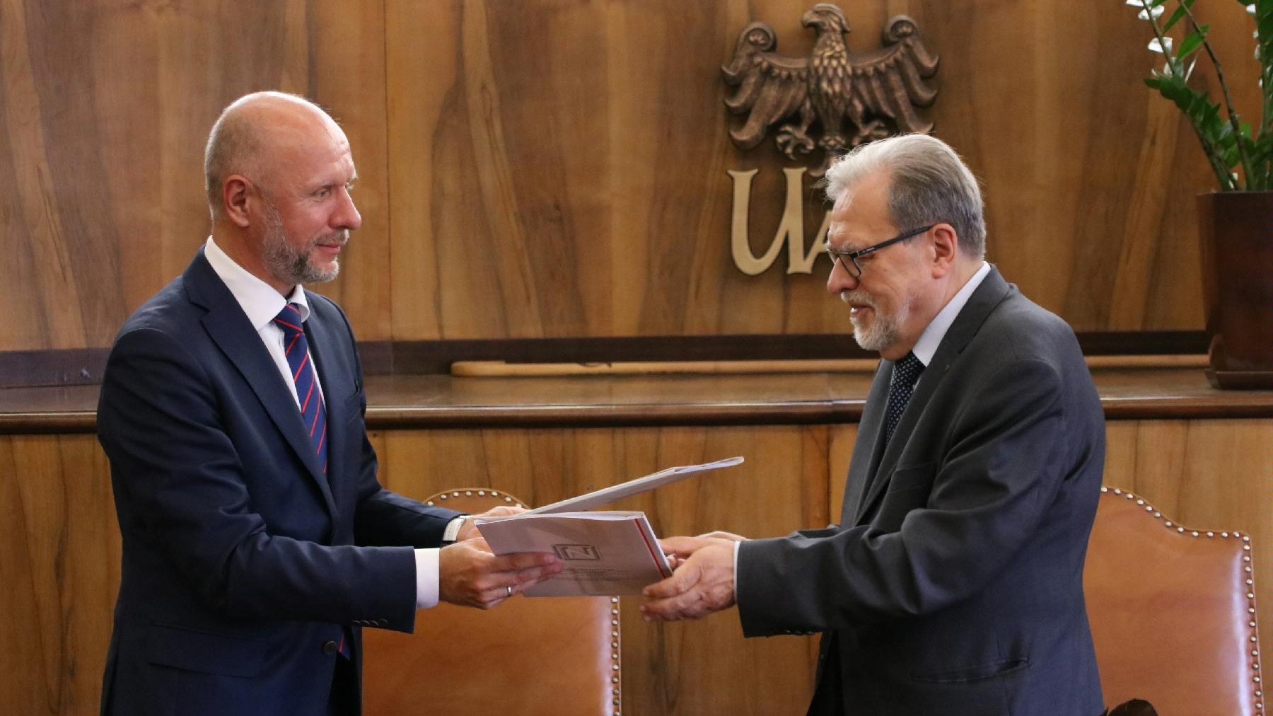 Na zdjęciu znajdują się rektor UAM Andrzej Lesicki i Bartosz Guss, wiceprezydent Poznania. Panowie wymieniają się umowami
