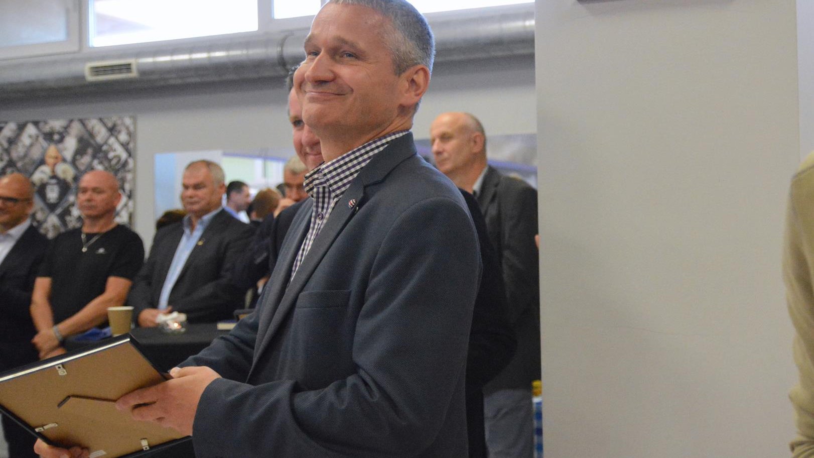 Jędrzej Solarski, zastępca prezydenta Poznania, stoi uśmiechnięty, trzyma w ręku oficjalne podziękowania, oprawione w ramkę