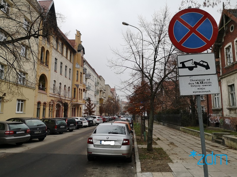 Dużo zaparkowanych samochodów po obu stronach ulicy - grafika rozmowy