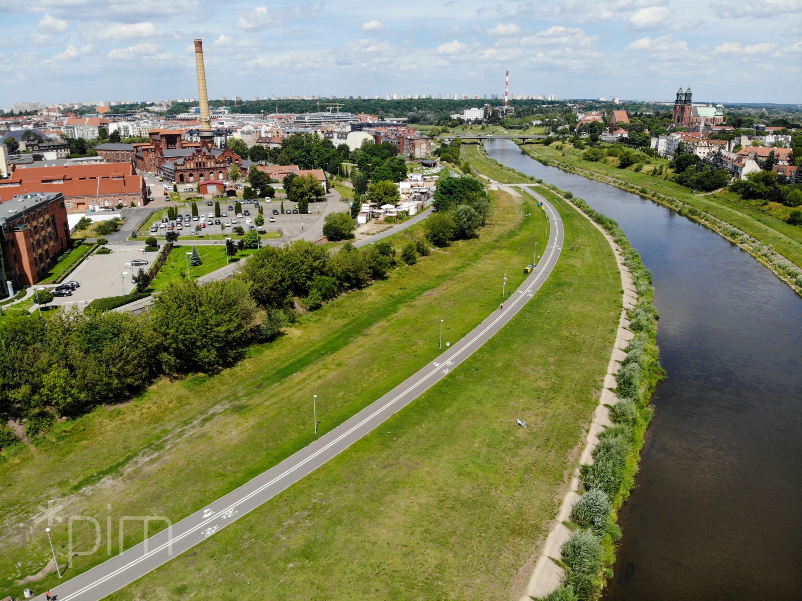 Zdjęcie przedstawia Wartostradę. Widać na nim drogę rowerową prowadzącą przez tereny zieleni. W sąsiedztwie znajdują się się zabudowania i rzeka. - grafika rozmowy