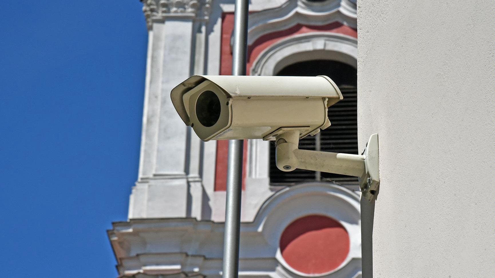 Zdjęcie przedstawia kamerę, zamontowaną na budynku urzędu przy placu Kolegiackim. Fotografia ukazuje zbliżenie na kamerę.