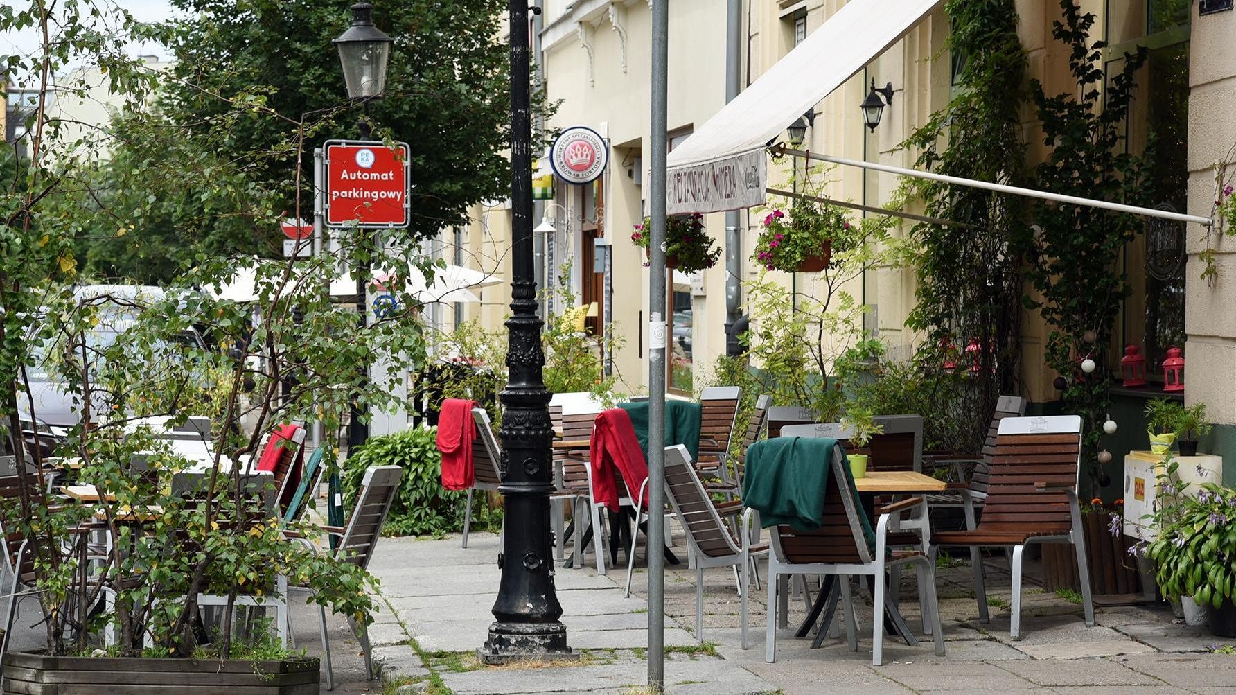 Na zdjęciu ogródek restauracyjny, na pierwszym planie krzesła z narzuconymi kocami i stoliki