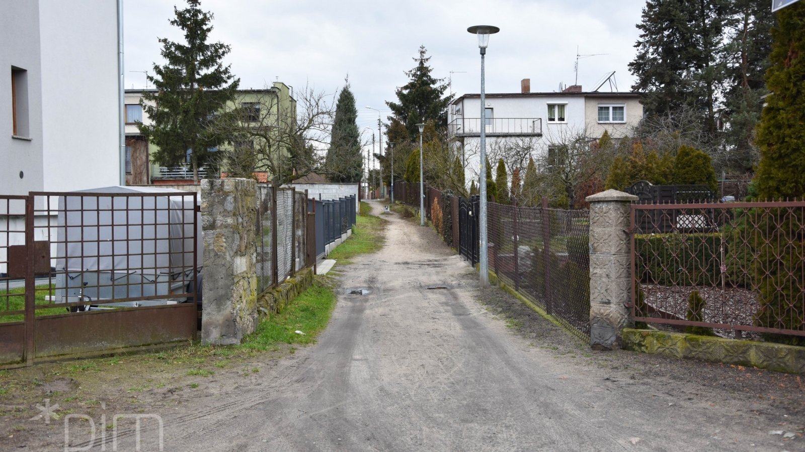 Na zdjęciu niewielka ulica, po obu jej stronach domy jednorodzinne