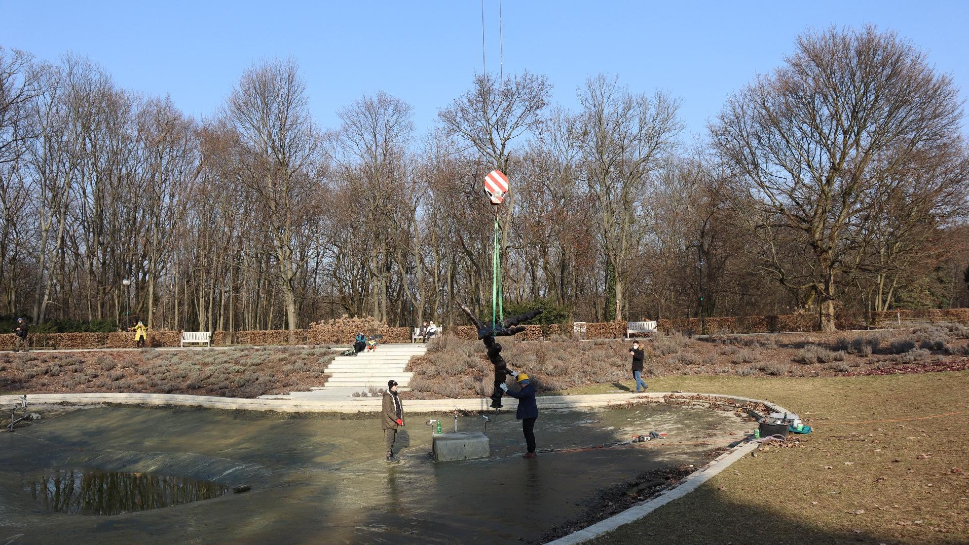 Rzeźba za pomocą liny i dźwigu jest mocowana na postumencie.