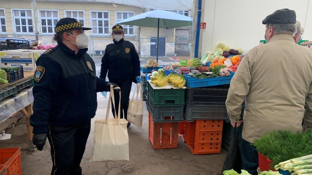 Na zdjęciu straznicy na targowisku, w rękach mają torby z maseczkami, które zaraz rozdadzą kupcom