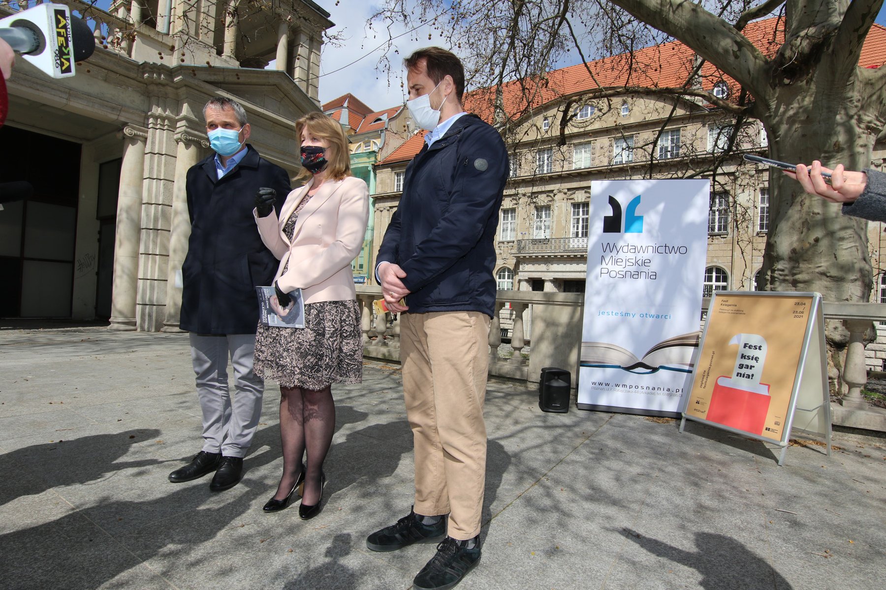 Zdjęcie przedstawia wiceprezydenta Jędrzeja Solarskiego, dyrektorkę Wydawnictwa Miejskiego Posnania - Katarzynę Kamińską oraz radnego miejskiego Grzegorza Jurę, stojących na placu przed Arkadią. - grafika rozmowy