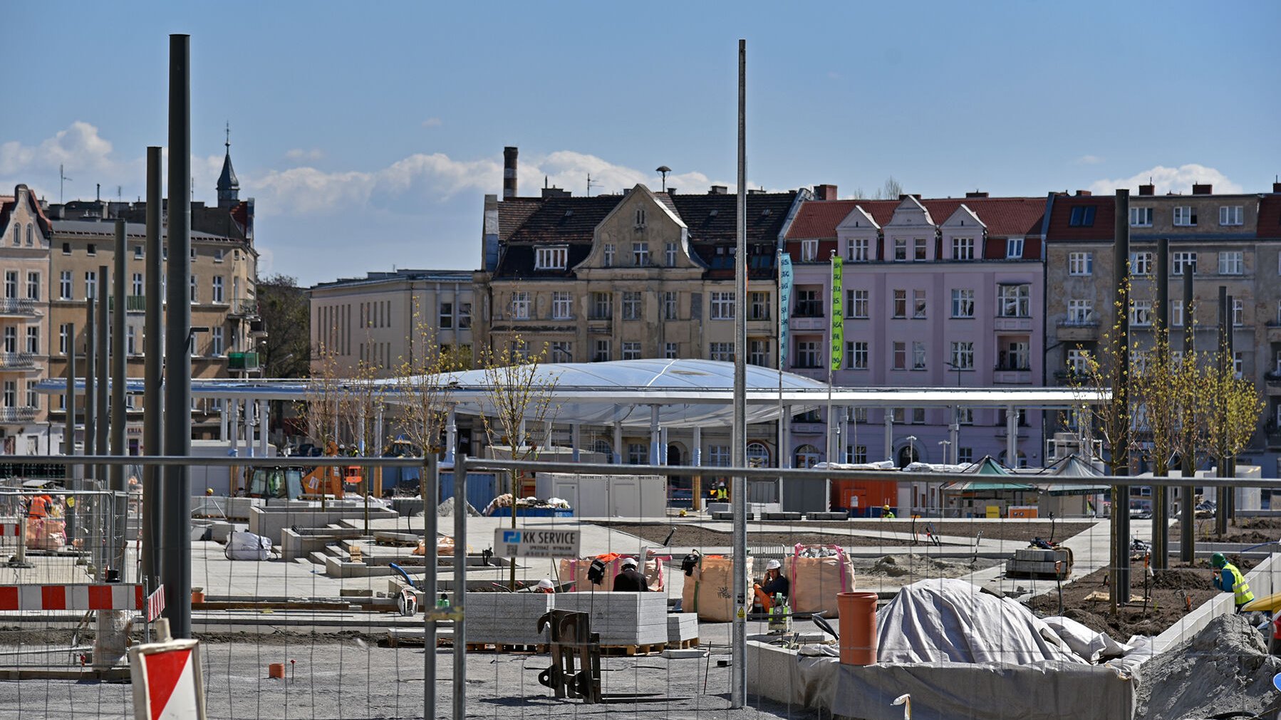 Na zdjęciu plac budowy na rynku, widać pompowane zadaszenie, w tle kamienice, z boku nowo posadzone drzewa