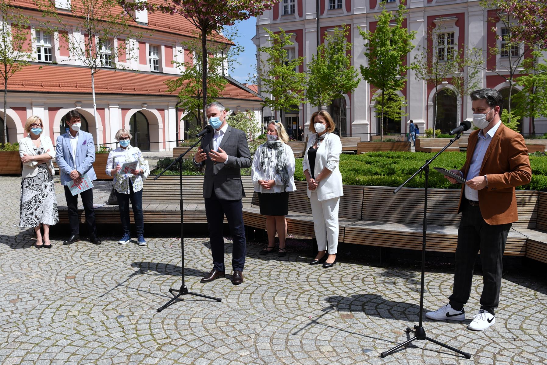 Zdjęcie z konferencji prasowej. W centrum, przy mikrofonie Jędrzej Solarski, wokół niego organizatorzy wydarzeń kulturalnych. Obok przy mikrofonie Marcin Kostaszuk - grafika rozmowy