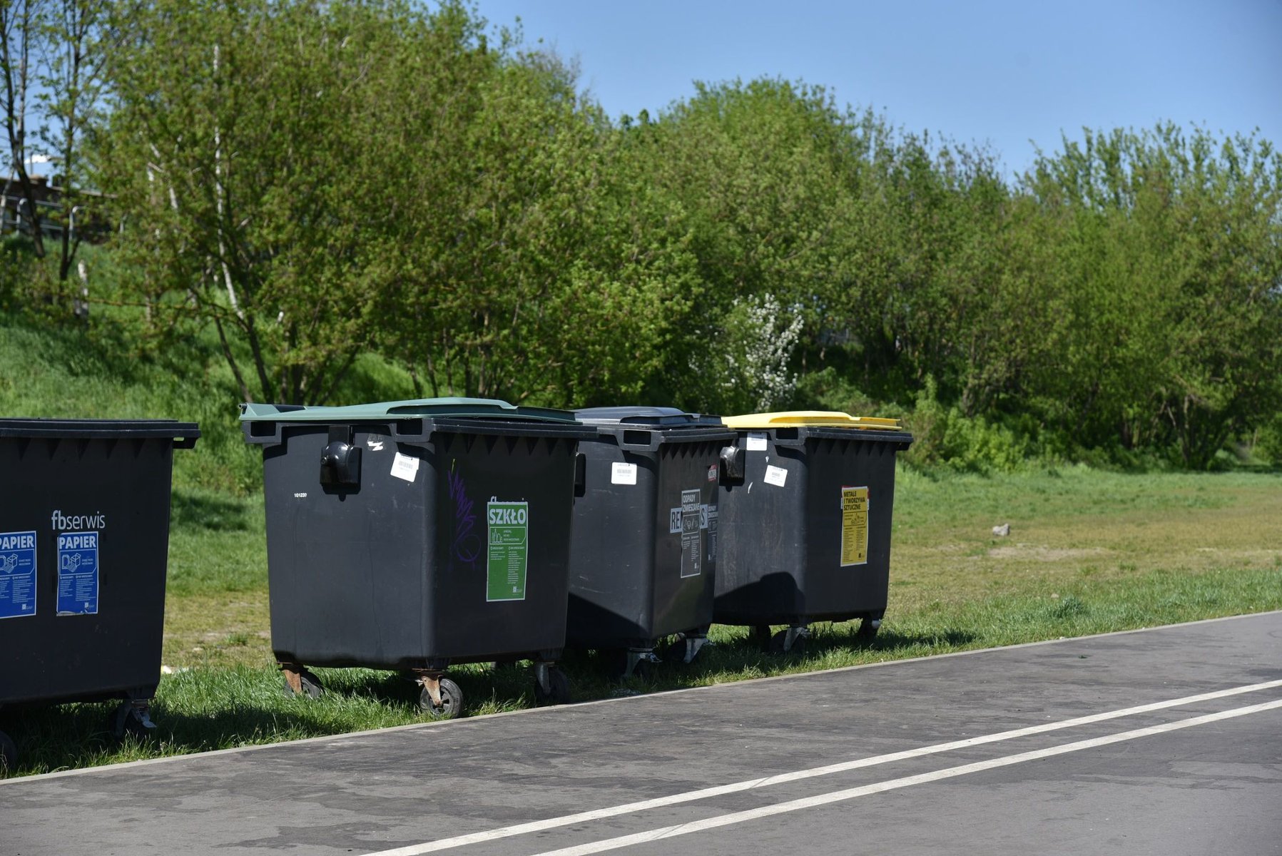 Zdjęcie: dolina Warty, na pierwszym planie Wartostrada, obok cztery pojemniki na śmieci, w tle drzewa - grafika rozmowy