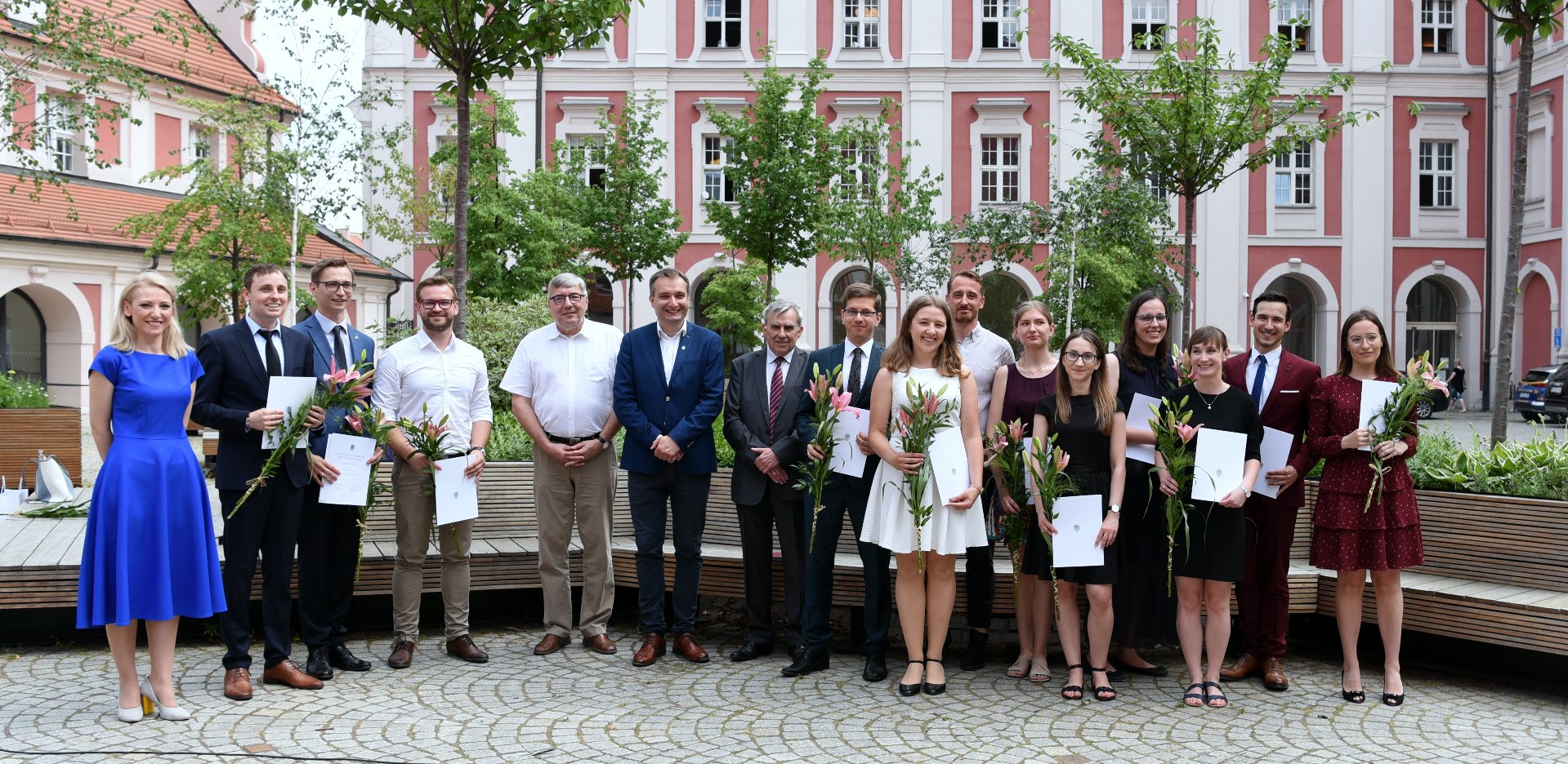 Na zdjęciu stypendyści na dziedzińcu urzędu miasta - zdjęcie grupowe - grafika rozmowy