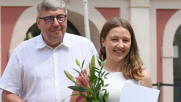 Dziedziniec Urzędu Miasta Poznania. Stypendystka trzymająca w ręku kwiat, obok niej Grzegorz Ganowicz