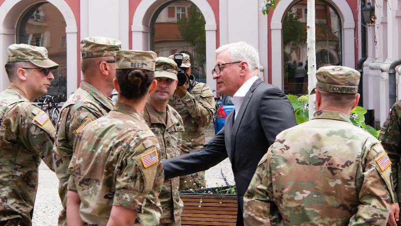 Dziedziniec Urzędu Miasta Poznania. Na nim żołnierze w mundurach, jednemu z nich podaje rękę Jacek Jaśkowiak, prezydent Poznania