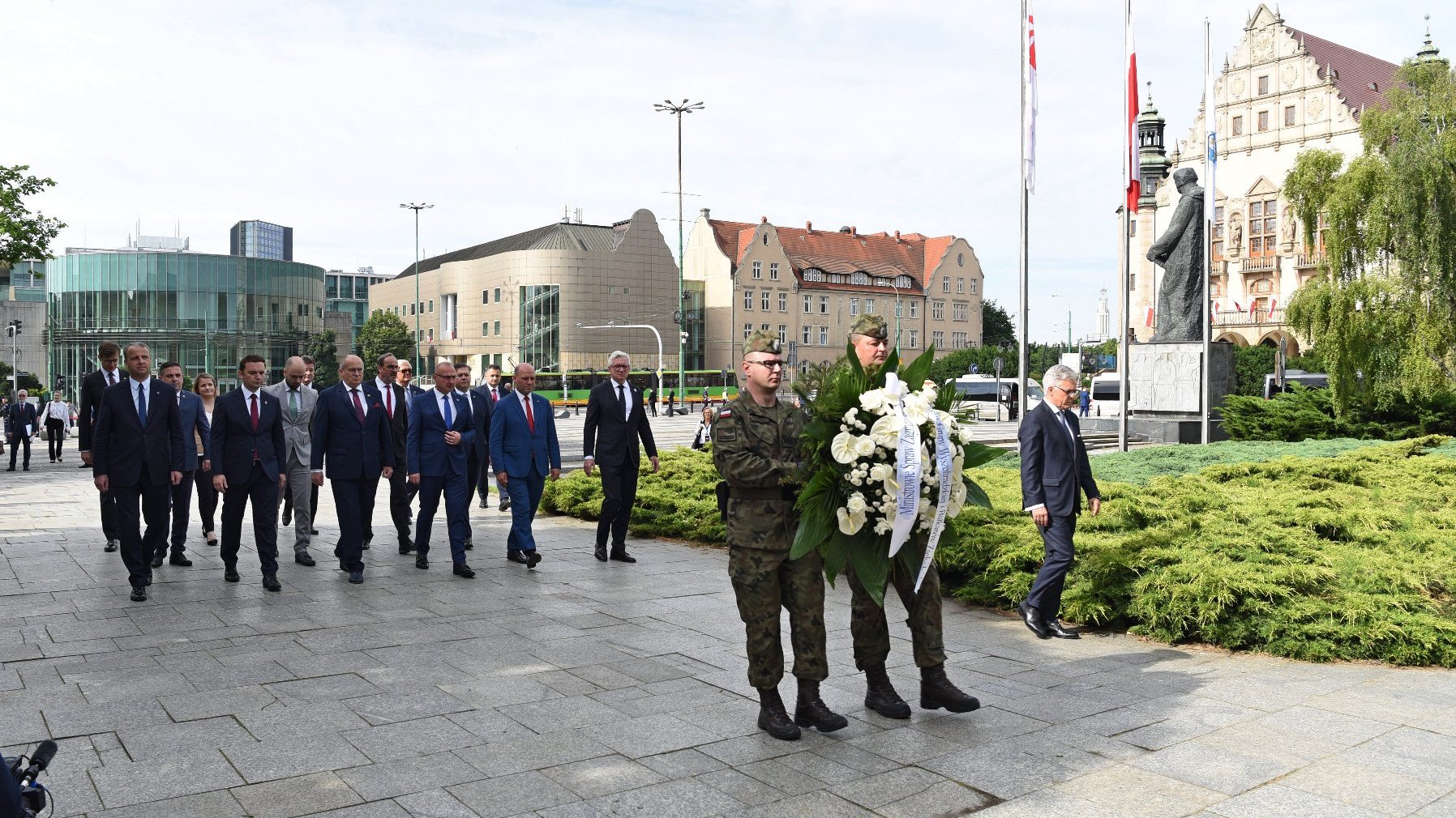 Plac Mickiewicza. Na pierwszym planie żołnierze z wiązanką białych kwiatów, za nimi grupa mężczyzn, wśród nich Jacek Jaśkowiak, prezydent Poznania