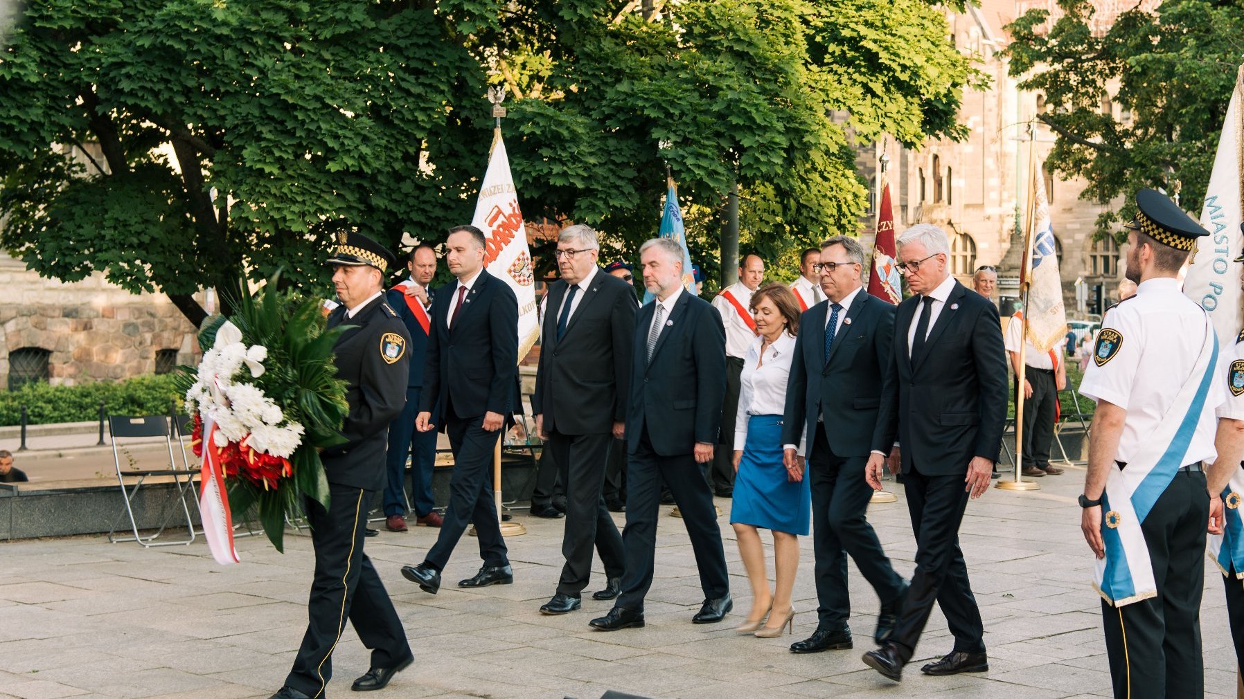 Na zdjęciu grupa samorządowców - wśród nich Jacek Jaśkowiak - składa kwiaty pod pomnikiem. Na pierwszym planie strażnik miejski z wiązanką