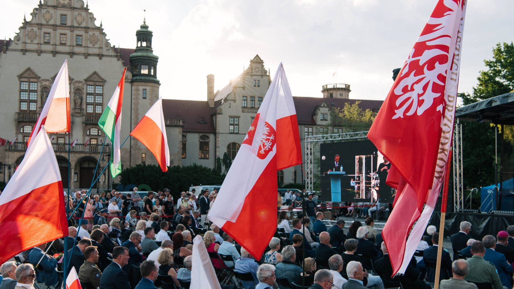 Tłum ludzi na placu Adama Mickiewicza, nad nimi powiewają flagi