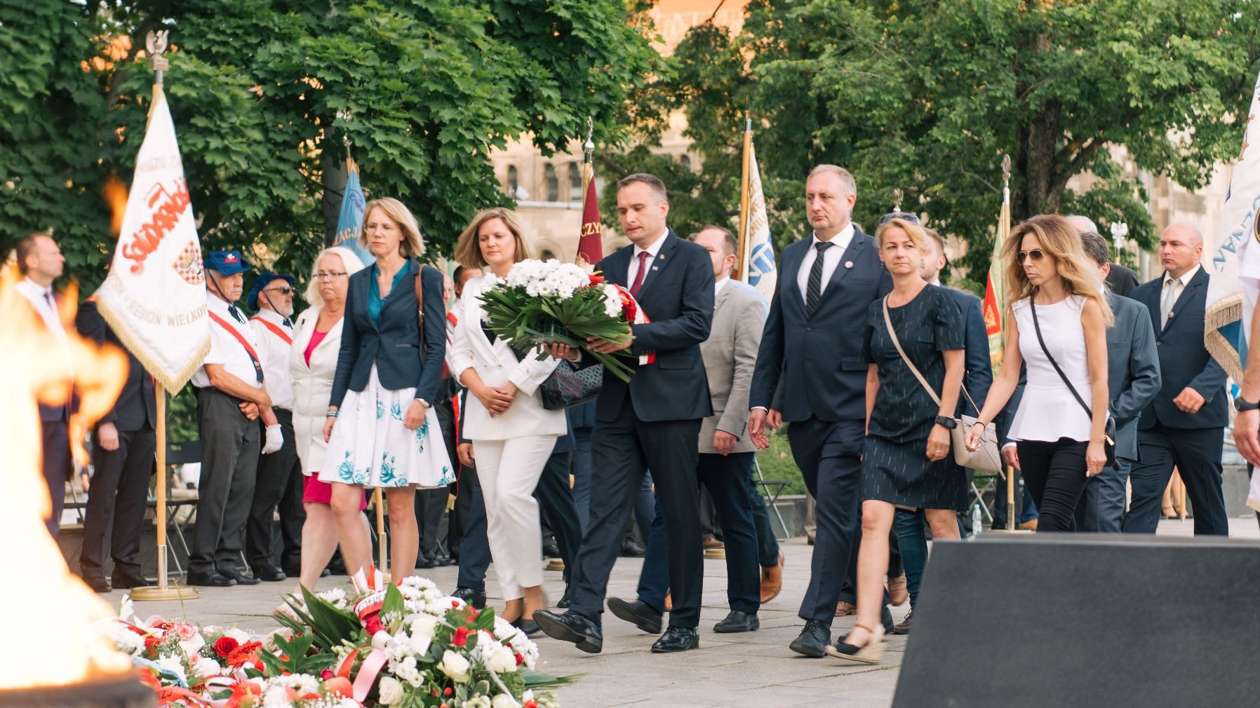 Grupa kobiet i mężczyzn składająca kwiaty pod Pomnikiem Poznańskiego Czerwca, wśród nich Mariusz Wiśniewski, zastępca prezydenta Poznania