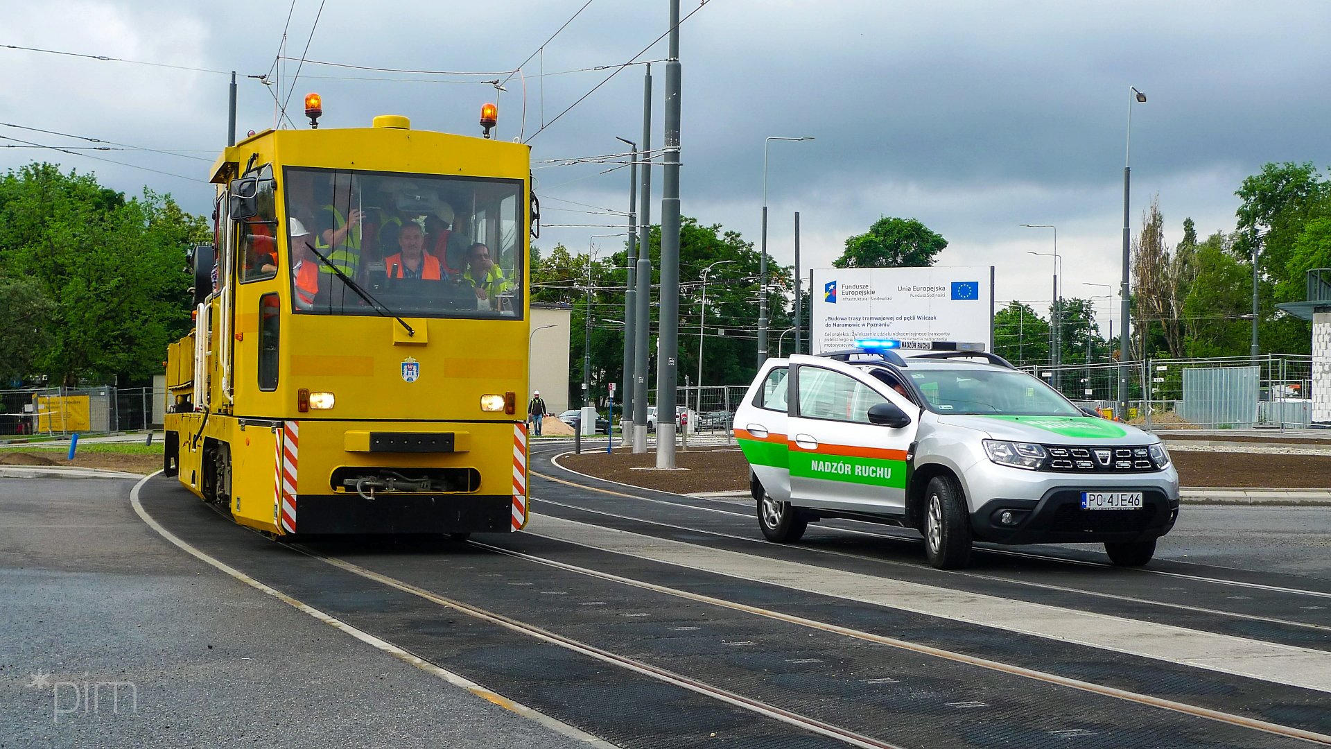 Na zdjęciu żółty pojazd testowy na torowisku, obok samochód Nadzoru Ruchu - grafika rozmowy