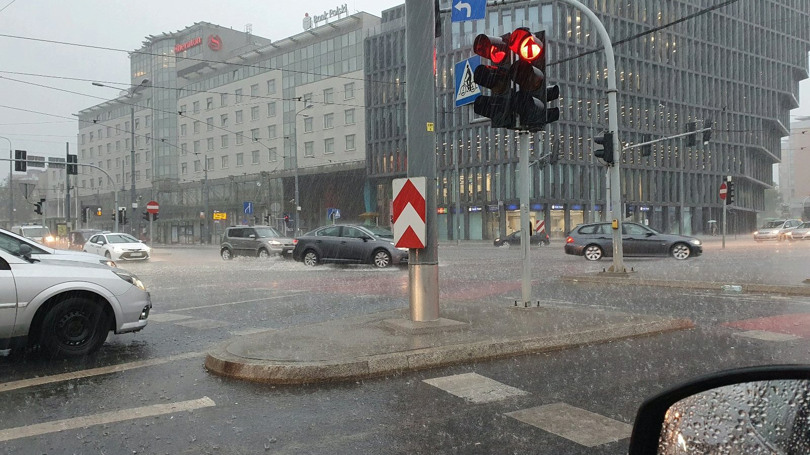 Zdjęcie przedstawia ulicę w deszczu. Widać na nim samochody i budynki. - grafika rozmowy