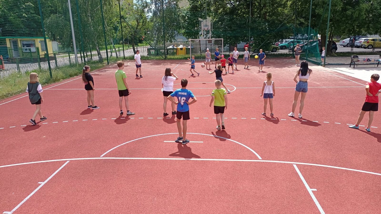 Zdjęcie przedstawia dzieci bawiące się na boisku.