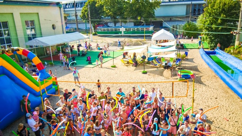 Zdjęcie przedstawia tłum ludzi na plaży w dawnej zajezdni tramwajowej.