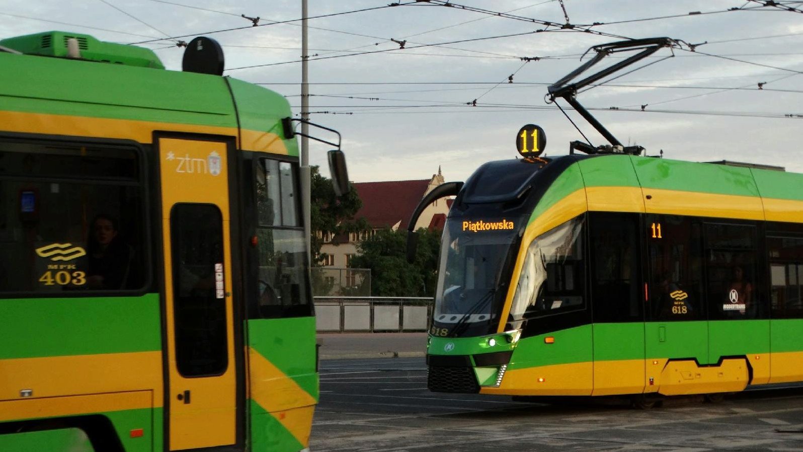 Na zdjęciu dwa tramwaje jadące po torowisku w przeciwne strony, jeden z nich to pojazd linii 11, z napisem "Piątkowska"