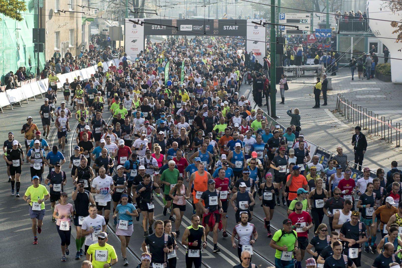 Zdjęcie przedstawia biegaczy podczas Poznańskiego Maratonu. Tłum ludzi biegnie ulicami Poznania. - grafika rozmowy