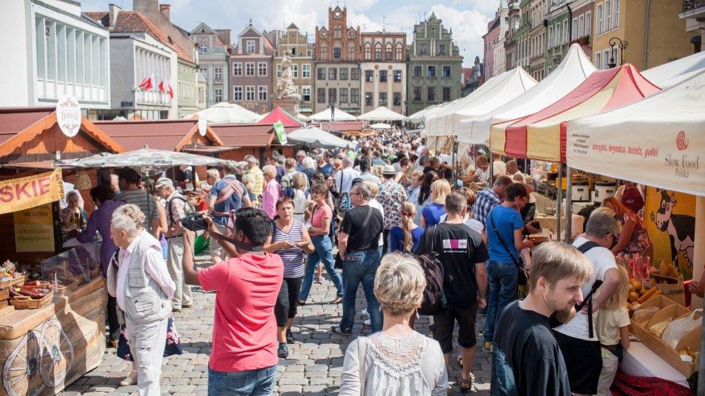 Zdjęcie przedstawia tłum ludzi na Starym Rynku pomiędzy straganami.