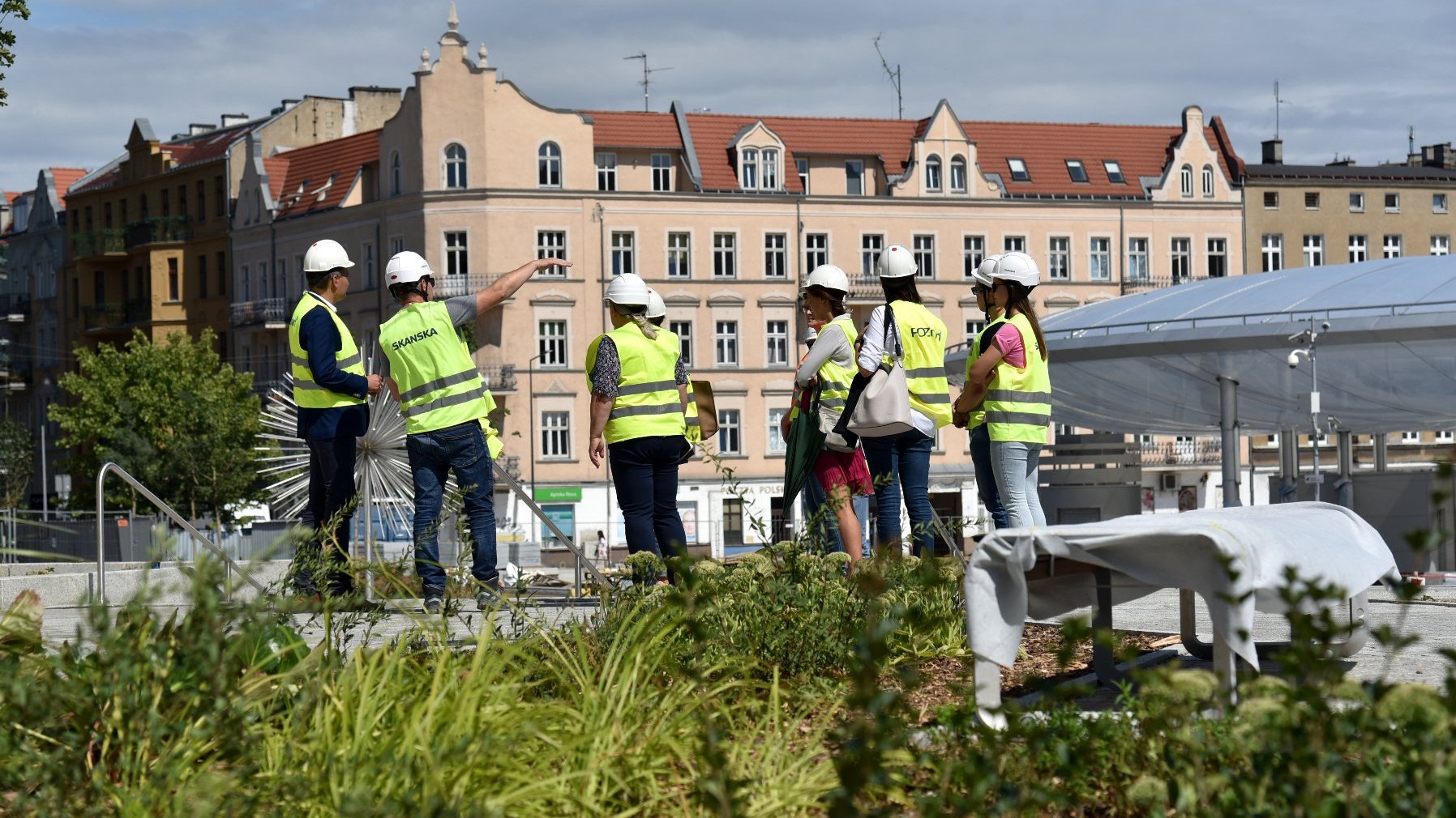 Grupa osób w kamizelkach. W tle rynek Łazarski.