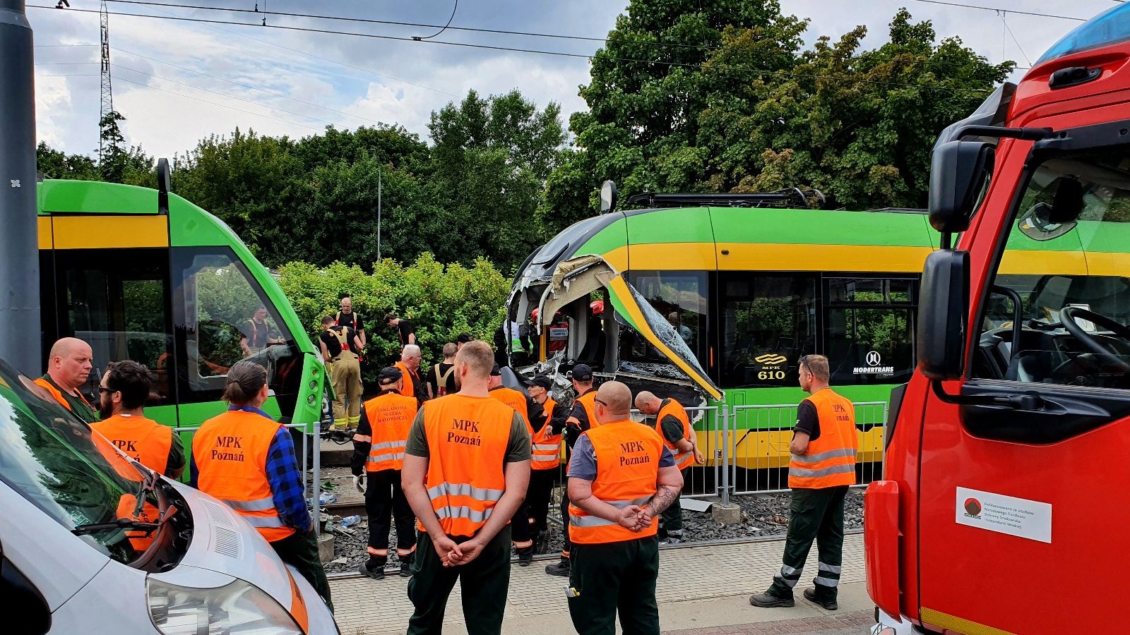 Na zdjęciu dwa tramwaje, jeden z nich ma całkowicie zniszczoną kabinę motorniczego, na pierwszym planie pracownicy MPK