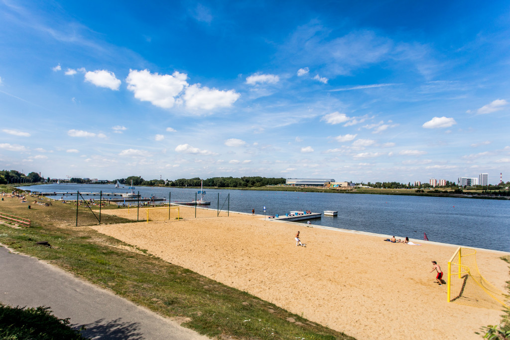 Na pierwszym planie plaża kąpieliska nad Maltą. W tle Termy Maltańskie. - grafika rozmowy