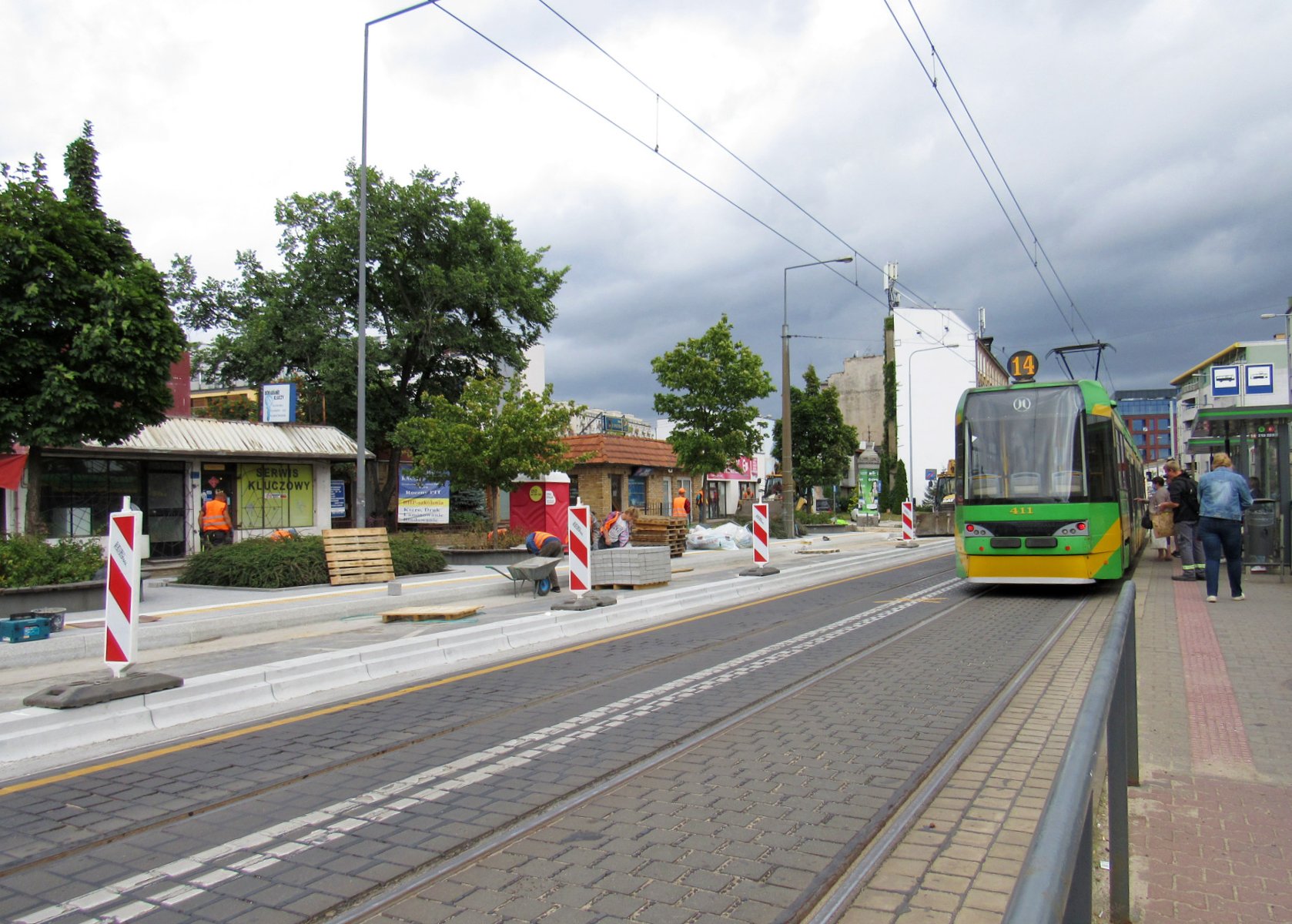 Dwa przystanki tramwajowe. Przy jednym stoi tramwaj, drugi przerabiany jest na wiedeński, widać płyty i słupki ostrzegające - grafika rozmowy