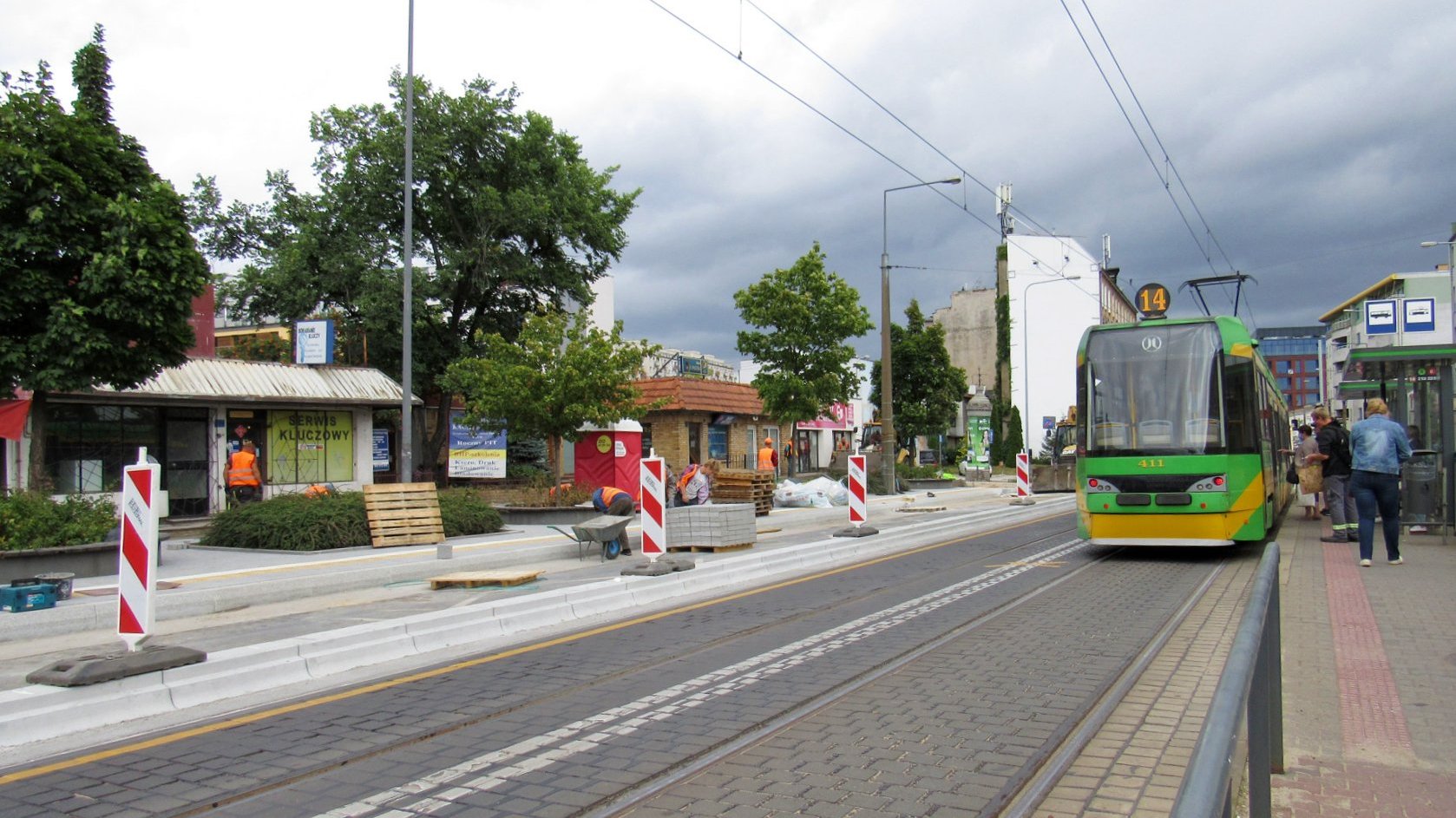 Dwa przystanki tramwajowe. Przy jednym stoi tramwaj, drugi przerabiany jest na wiedeński, widać płyty i słupki ostrzegające