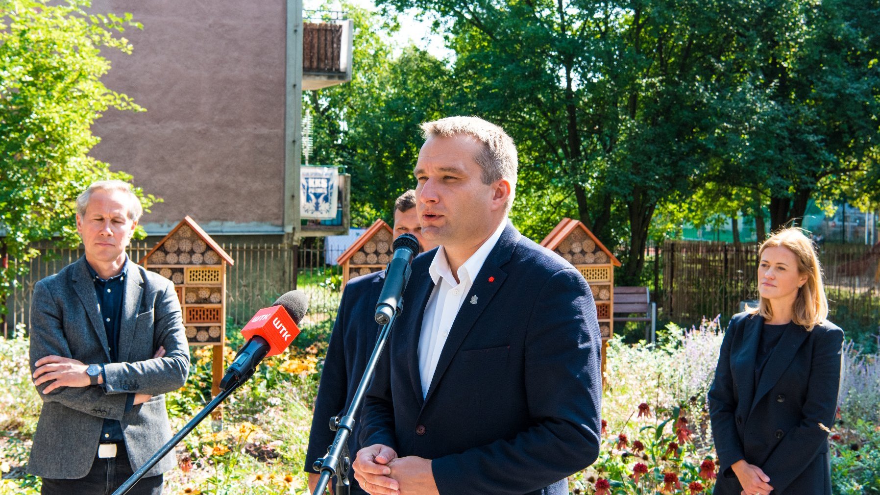 Galeria zdjęć przedstawia konferencję prasową na skwerze oraz sam skwer z zielenią i domkami dla owadów.