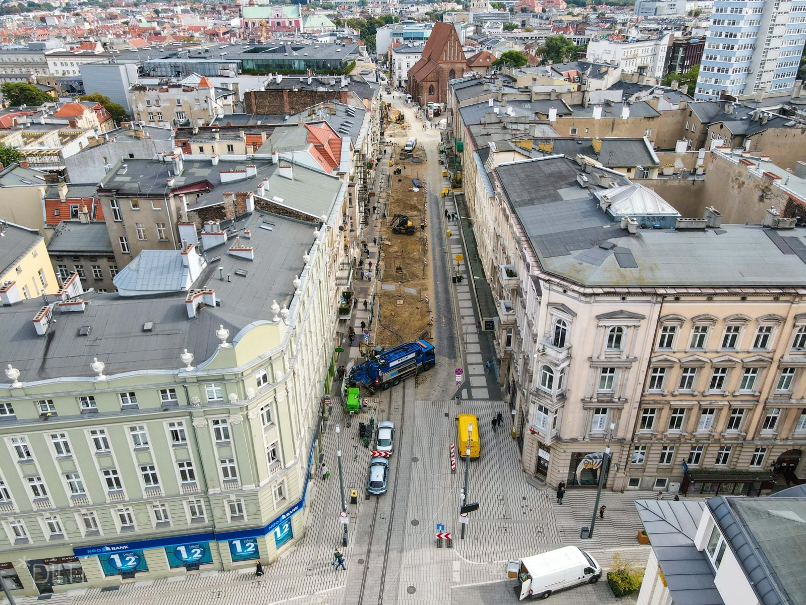 Na zdjęciu ulica Święty Marcin widziana z lotu ptaka, po obu stronach kamienice, w centrum plac budowy - grafika rozmowy