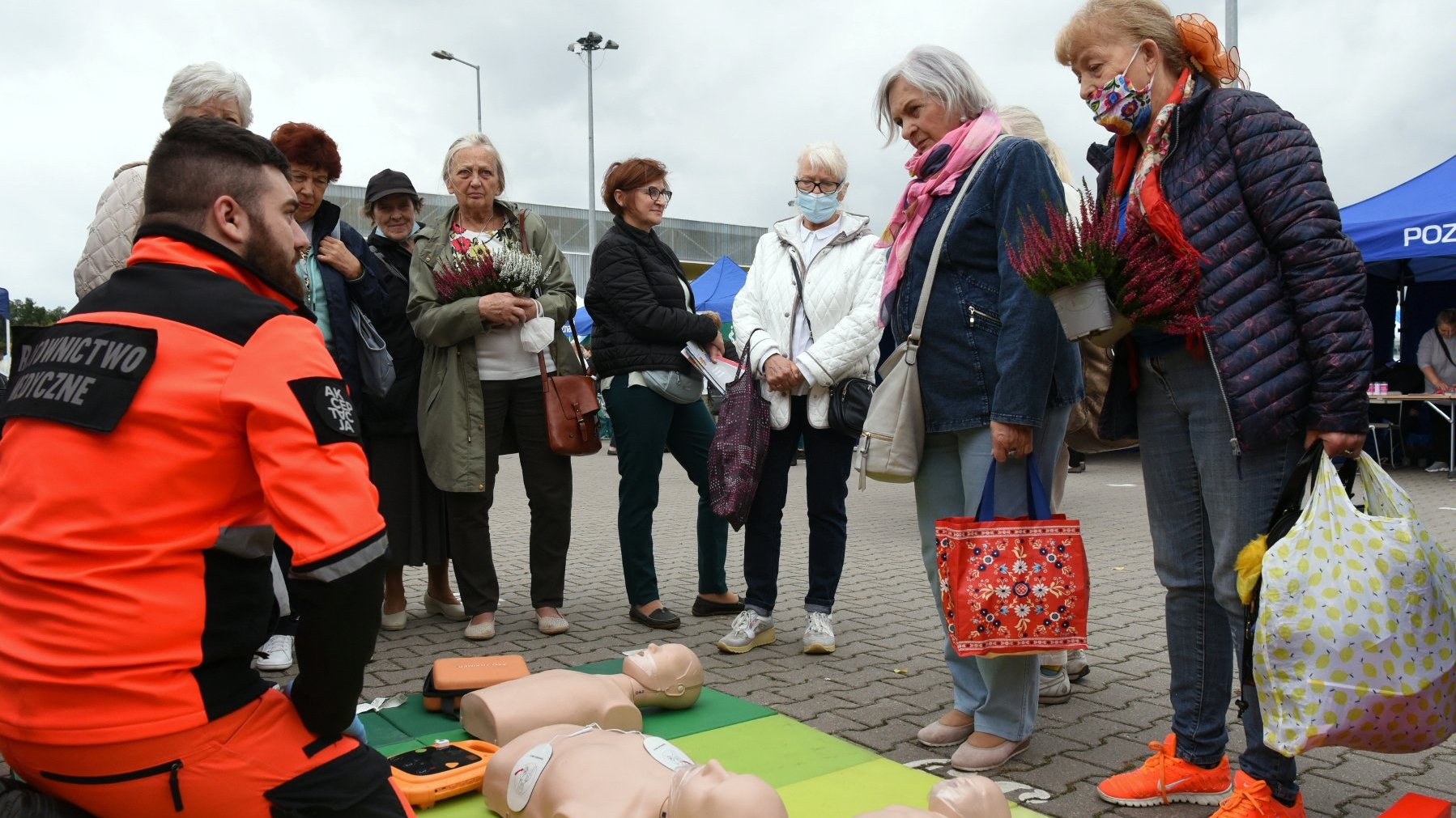 Pokaz pierwszej pomocy, seniorzy skupieni wokół ratownika