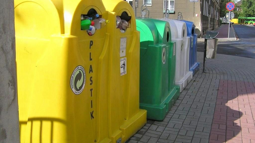 Na zdjęciu cztery kolorowe pojemniki na śmieci stojące obok siebie w rzędzie - grafika rozmowy