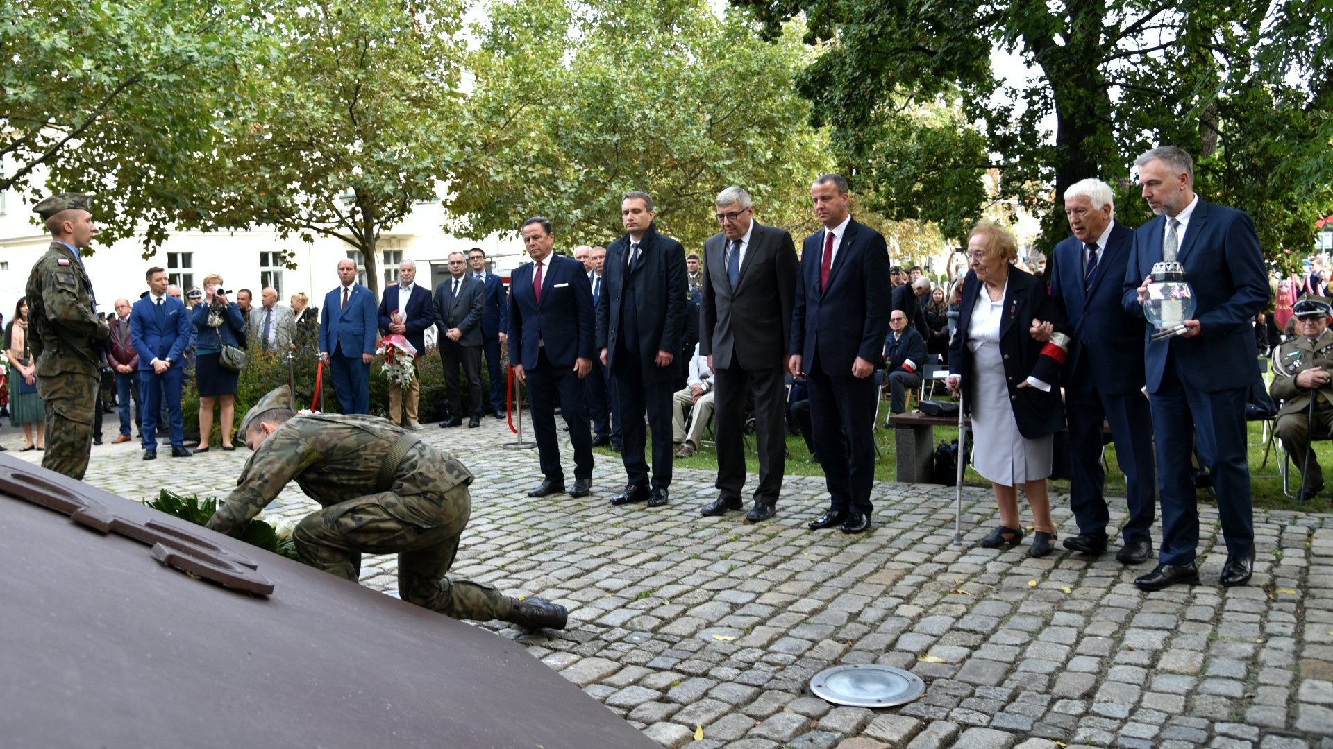 Zdjęcie przedstawia przedstawicieli władz samorządowych i wojewódzkich oraz kombatantów składających kwiaty pod pomnikiem.