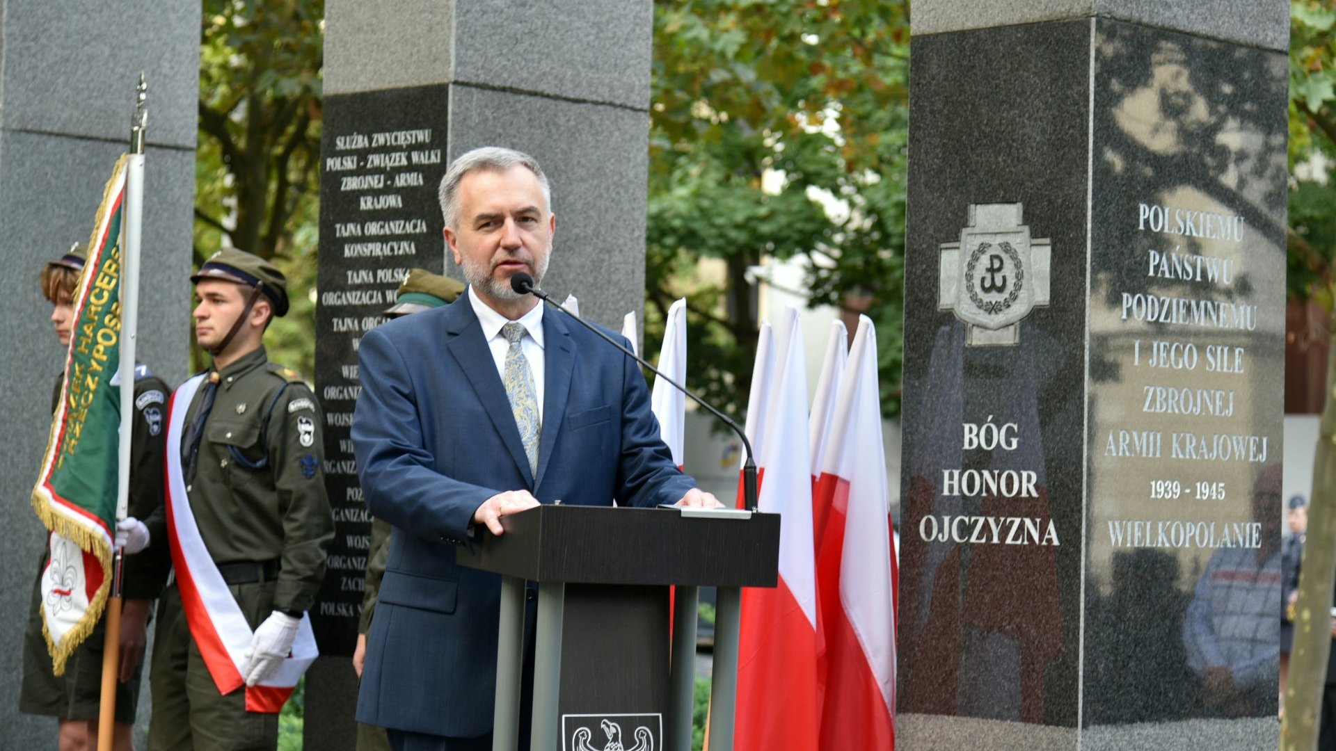 Zdjęcie przedstawia marszałka województwa wielkopolskiego przemawiającego za mównicą.