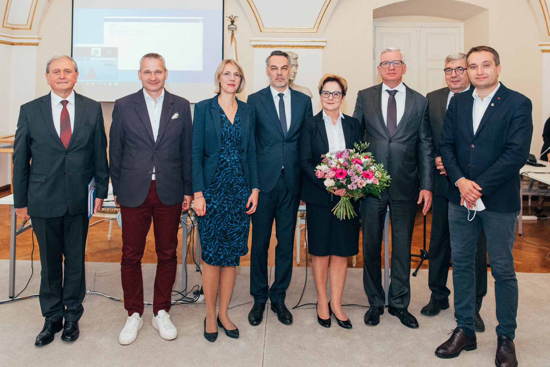 Grupa ludzi ustawiona do zdjęcia. W centrum była skarbnik i jej następca, obok prezydent Poznania, jego zastępcy, przewodniczący rady miasta, sekretarz i radna - grafika rozmowy