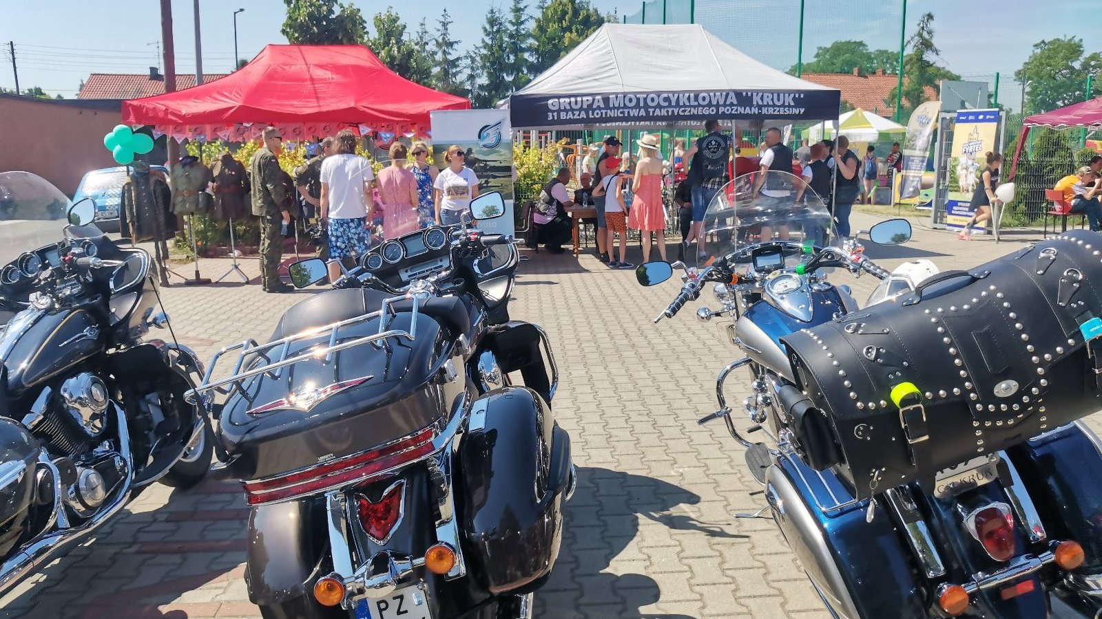 Zdjęcie przedstawia motocykle, kolorowe stoiska i tłum ludzi.