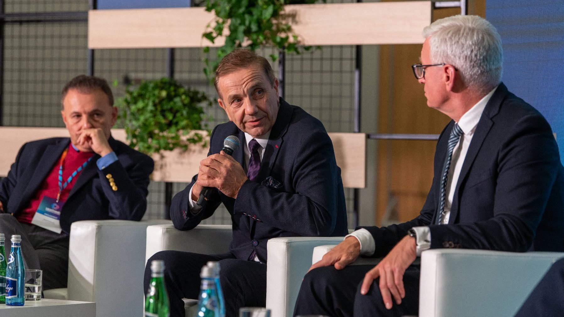 Trzej mężczyźni - paneliści, siedzą na scenie, wśród nich Jacek Jaśkowiak, prezydent Poznania