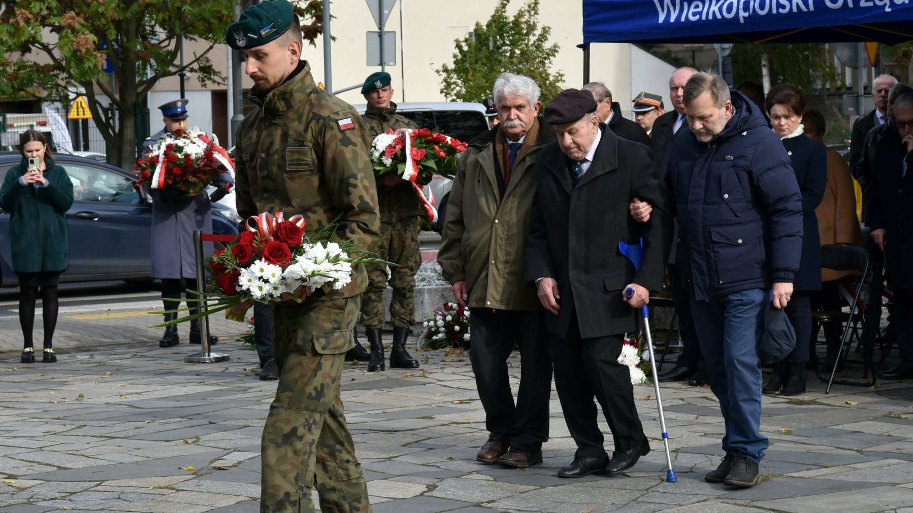 Na zdjęciu przedstawiciele kombatantów, przed nimi żołnierz trzymający wiązankę kwiatów