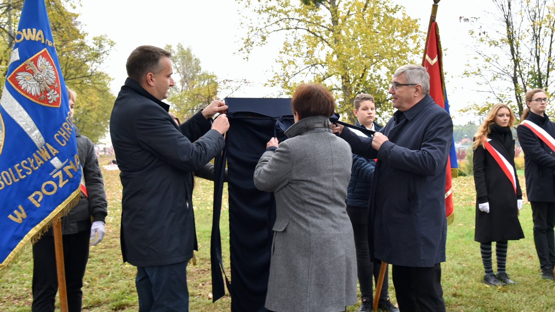 Zdjęcie przedstawia wiceprezydenta Poznania, przewodniczącego Rady Miasta Poznania oraz prezes ZNP podczas odsłaniania tablicy.