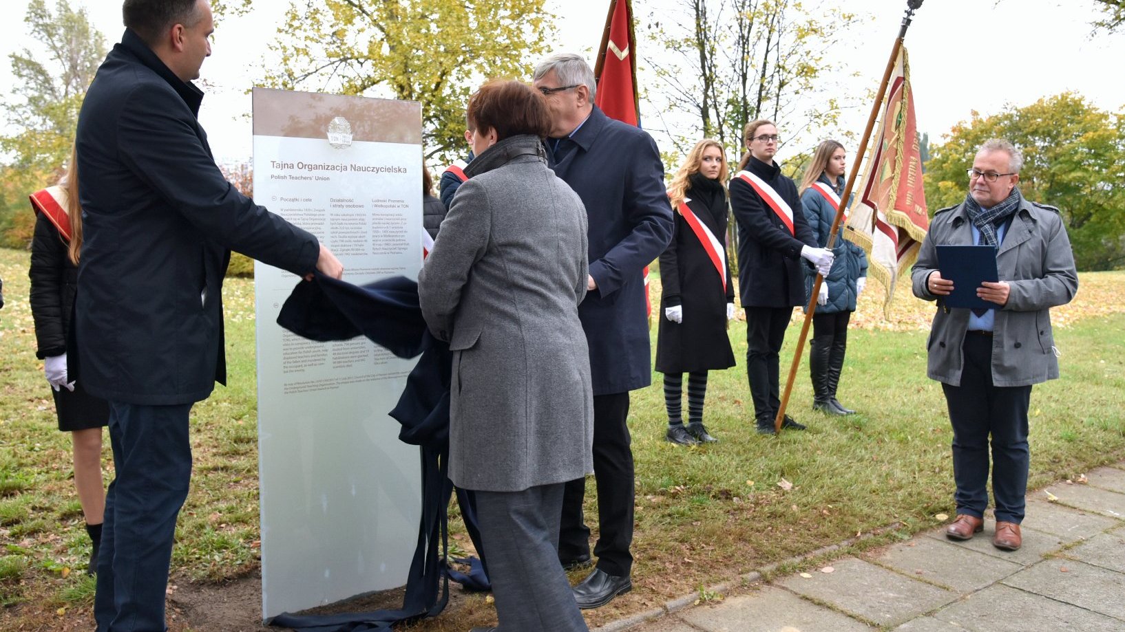 Zdjęcie przedstawia wiceprezydenta Poznania, przewodniczącego Rady Miasta Poznania oraz prezes ZNP podczas odsłaniania tablicy.