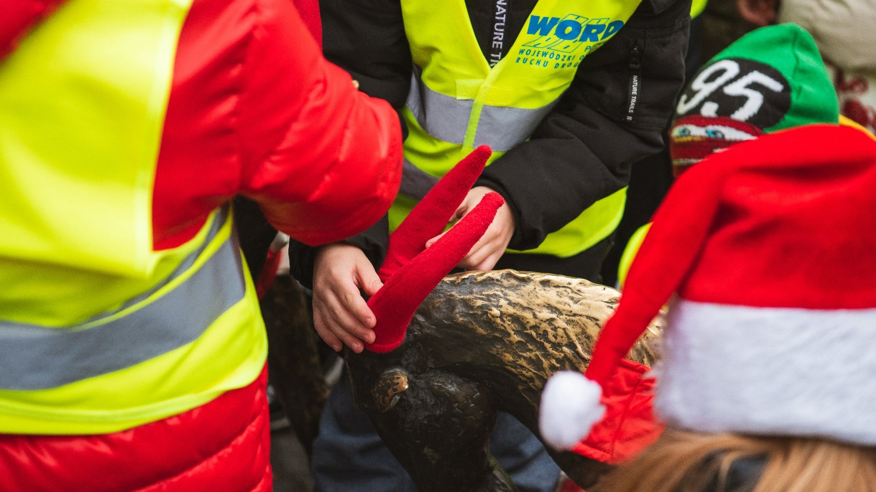 Dziecie ubierają pomnik koziołków w odświętne szaty - czerwone czapki na rogi i czerwone kubraczki.