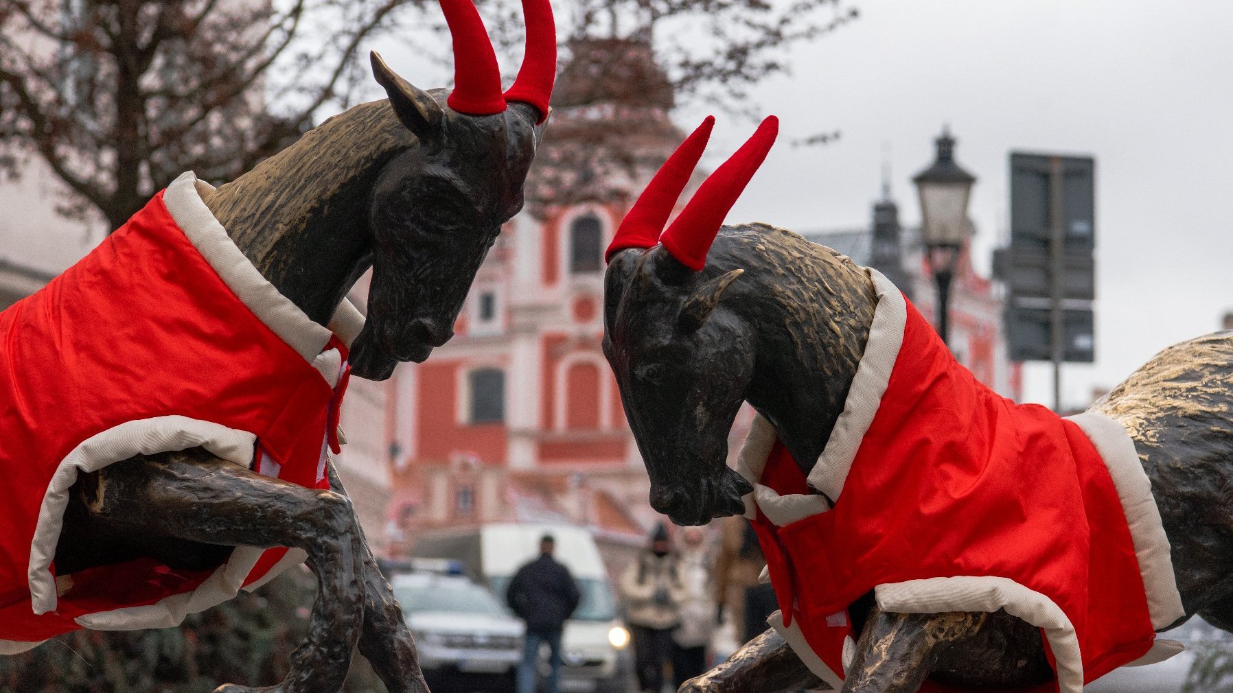 Pomnik koziołków ubrany w czerwone czapki na rogi i kubraczki.