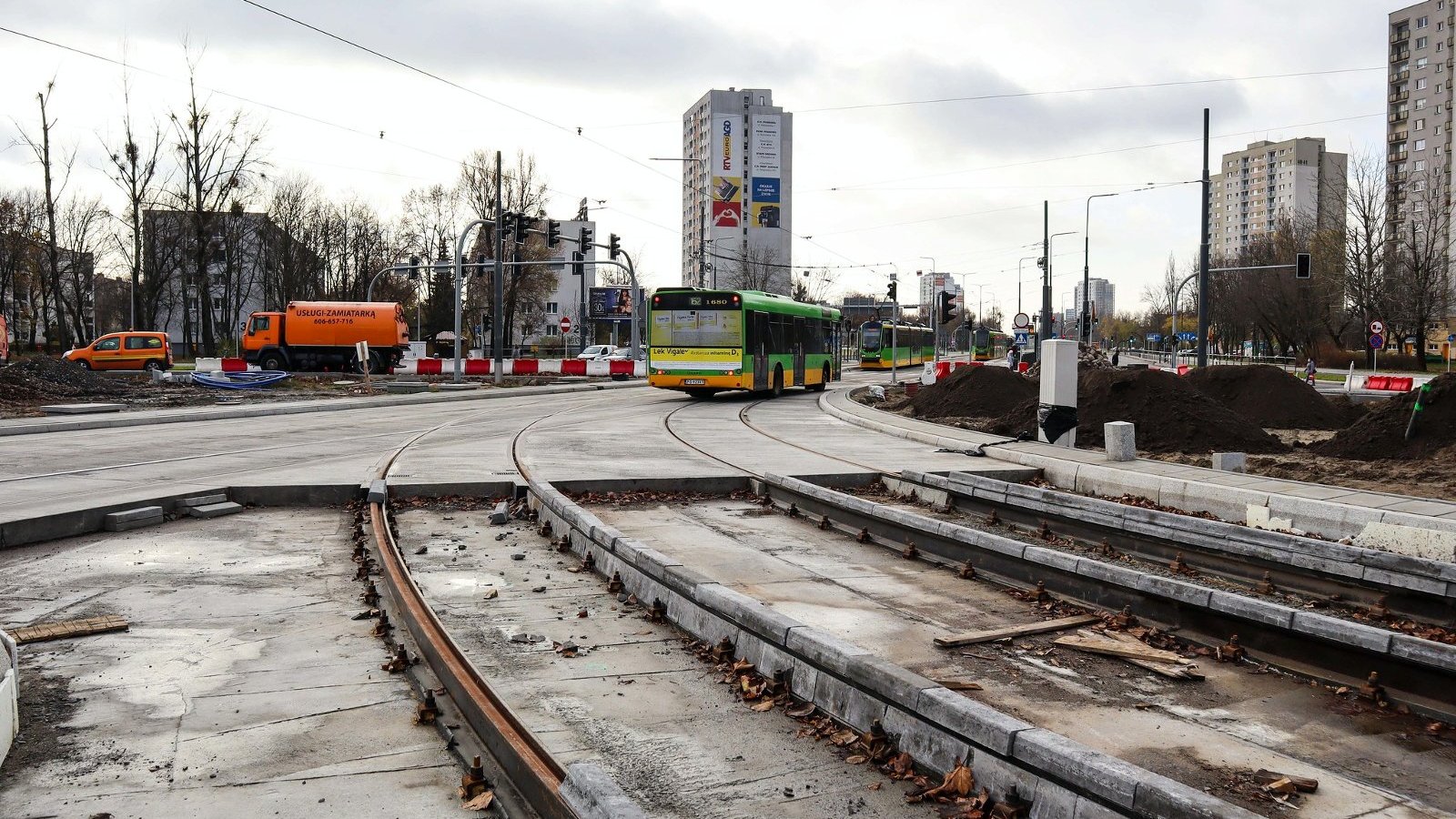 Autobus przejeżdża przez remontowane rondo. Na pierwszym planie remontowane tory tramwajowe.