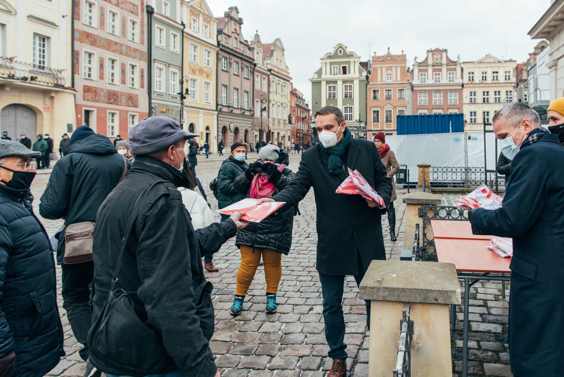 Galeria zdjęć przedstawia akcję rozdawania flag powstańczych poznaniakom na Starym Rynku. - grafika rozmowy