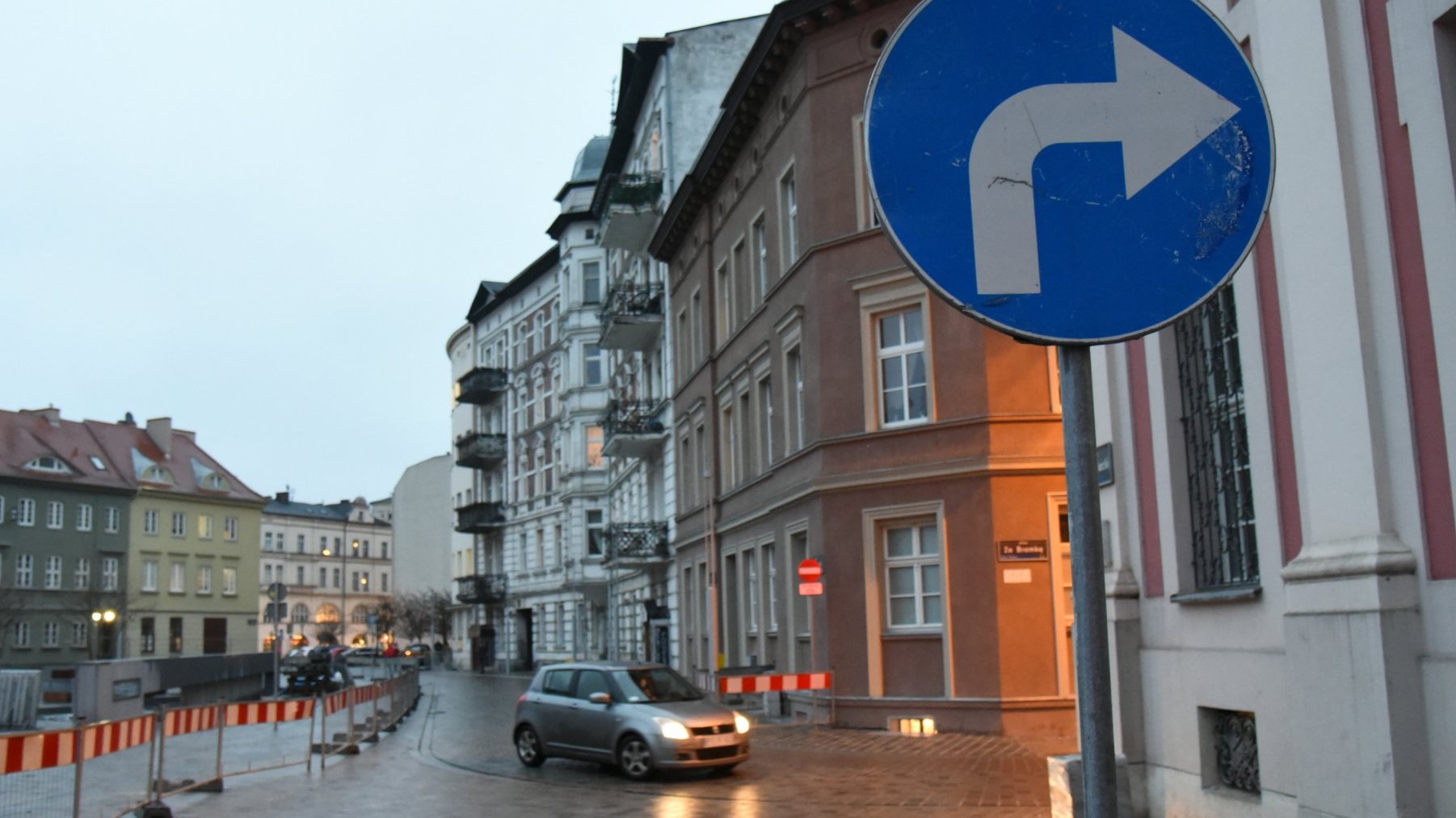 Na zdjęciu plac Kolegiacki, na pierwszym planie znak drogowy: nakaz skrętu w prawo